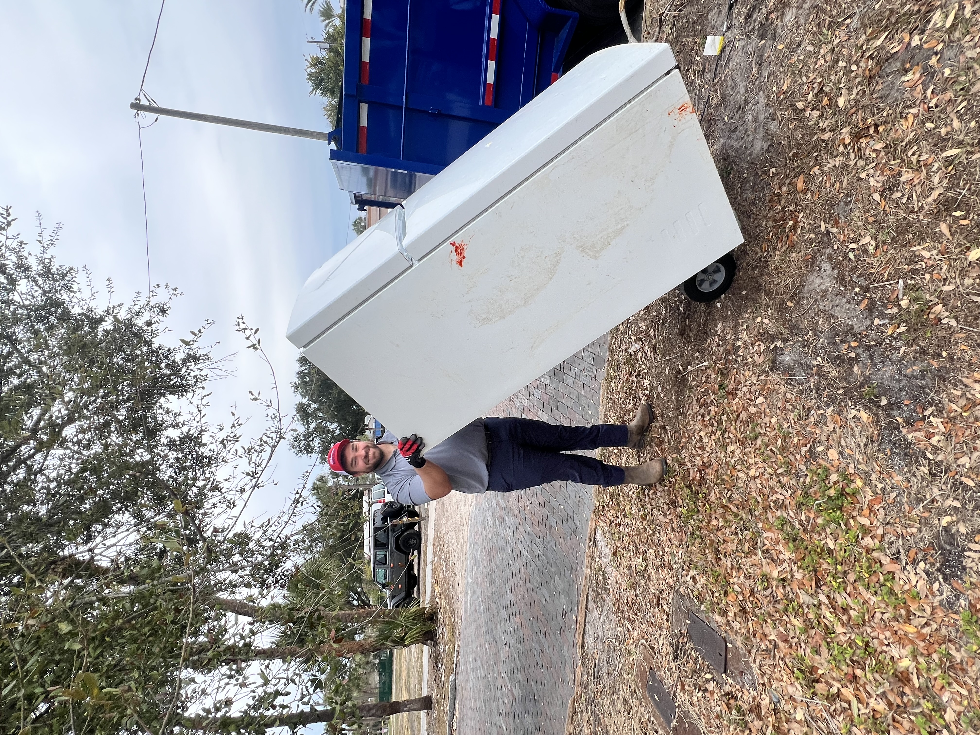 Team member hauling refrigerator on dolly