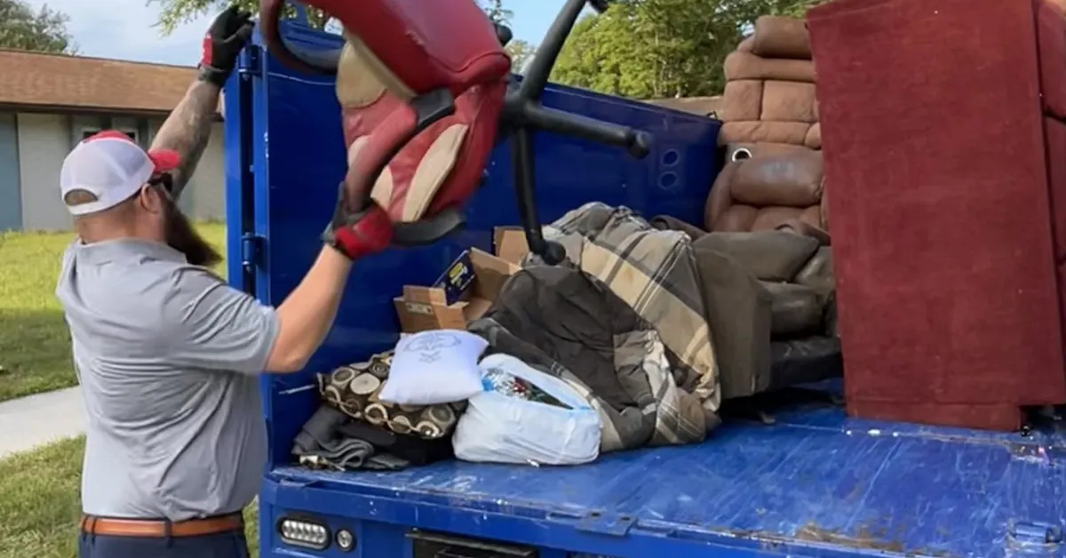Junk Nation Removal crew member loading furniture and bagged household items into the truck during a house cleanout