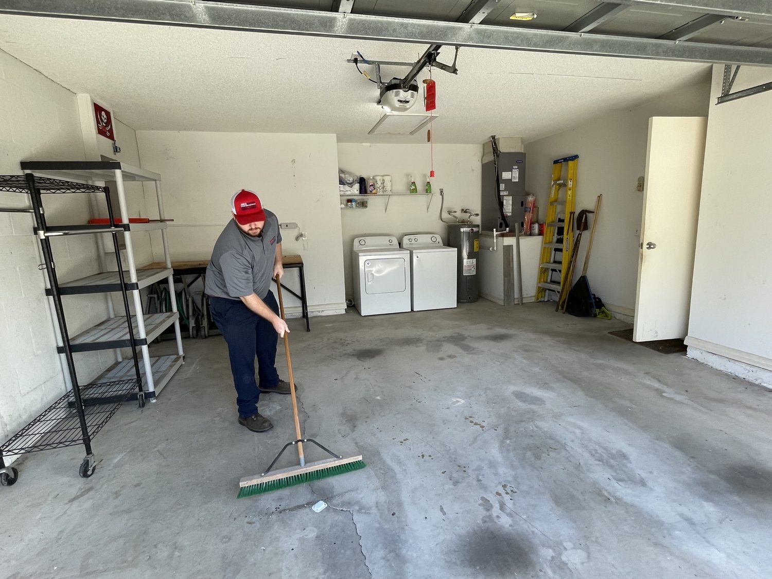 Junk Nation Removal crew member sweeping a cleared Tampa Bay garage after a household cleanout