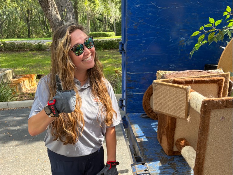 Junk Nation Removal team member giving a thumbs up beside a trailer of removed furniture