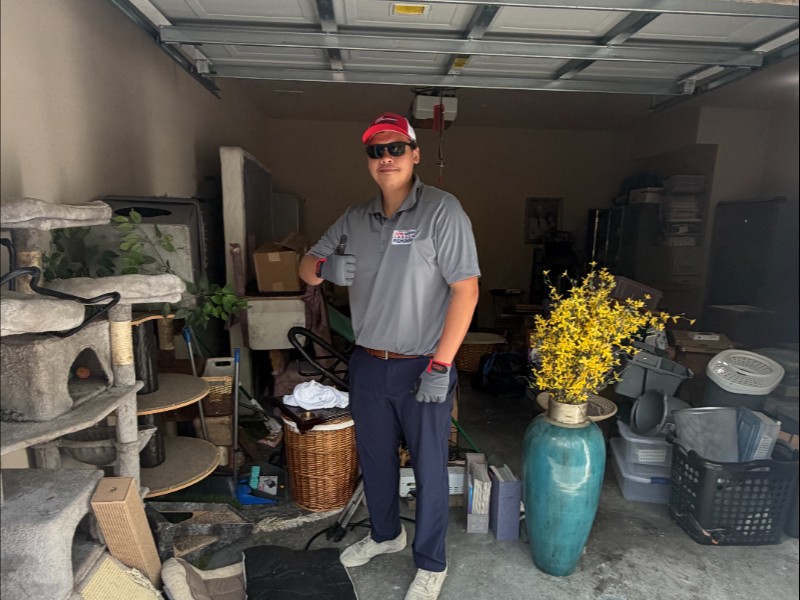 Junk Nation Removal team member inside a cluttered garage before a cleanout