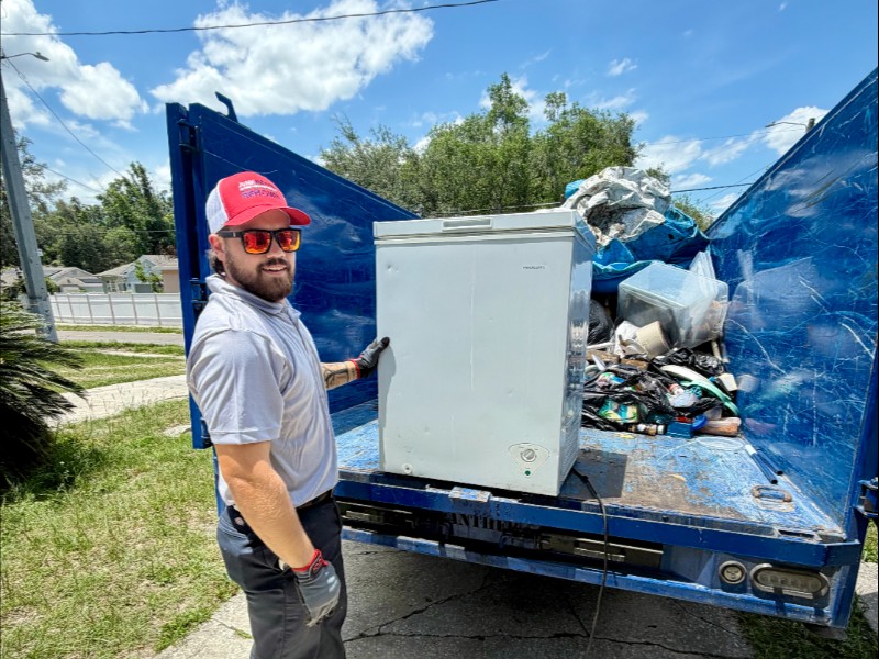 Junk Nation Removal crew member removing a chest freezer and bagged household junk