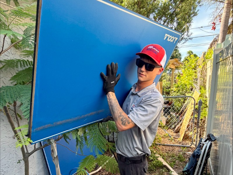 Junk Nation Removal team member hauling away a folding table from a backyard