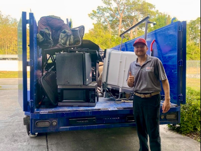 Junk Nation Removal crew with a fully loaded trailer of appliances and household items