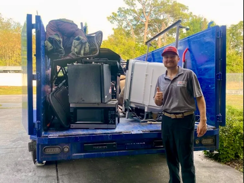 Junk Nation Removal crew with a fully loaded trailer of appliances and household items