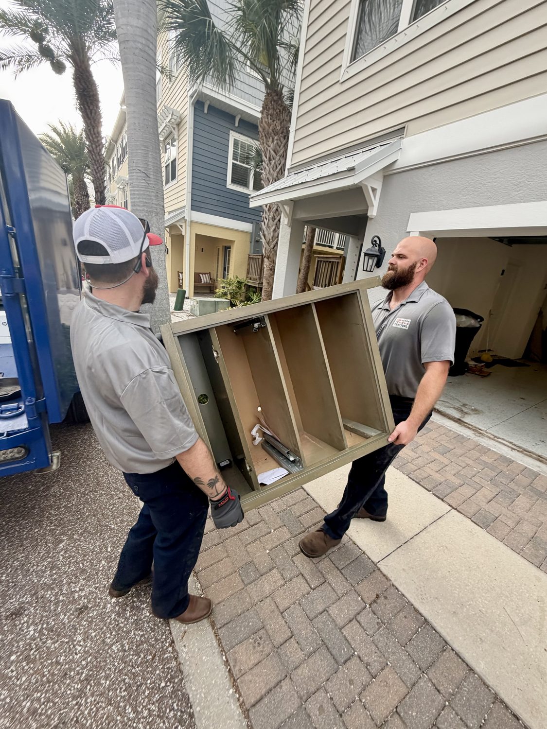 Junk Nation Removal team carrying a cabinet out of a Tampa Bay home