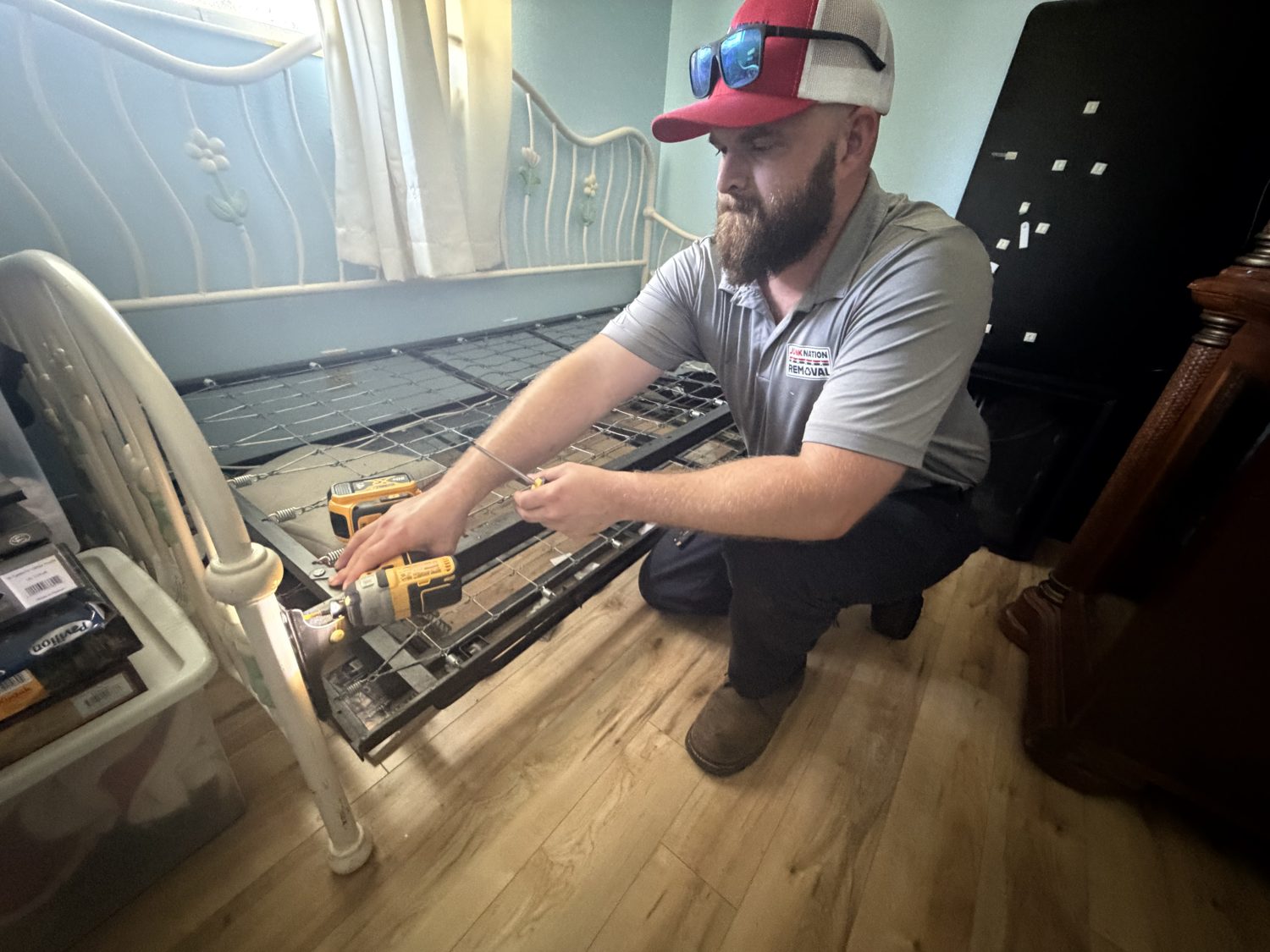 Junk Nation Removal team member disassembling a bed frame during a senior downsizing