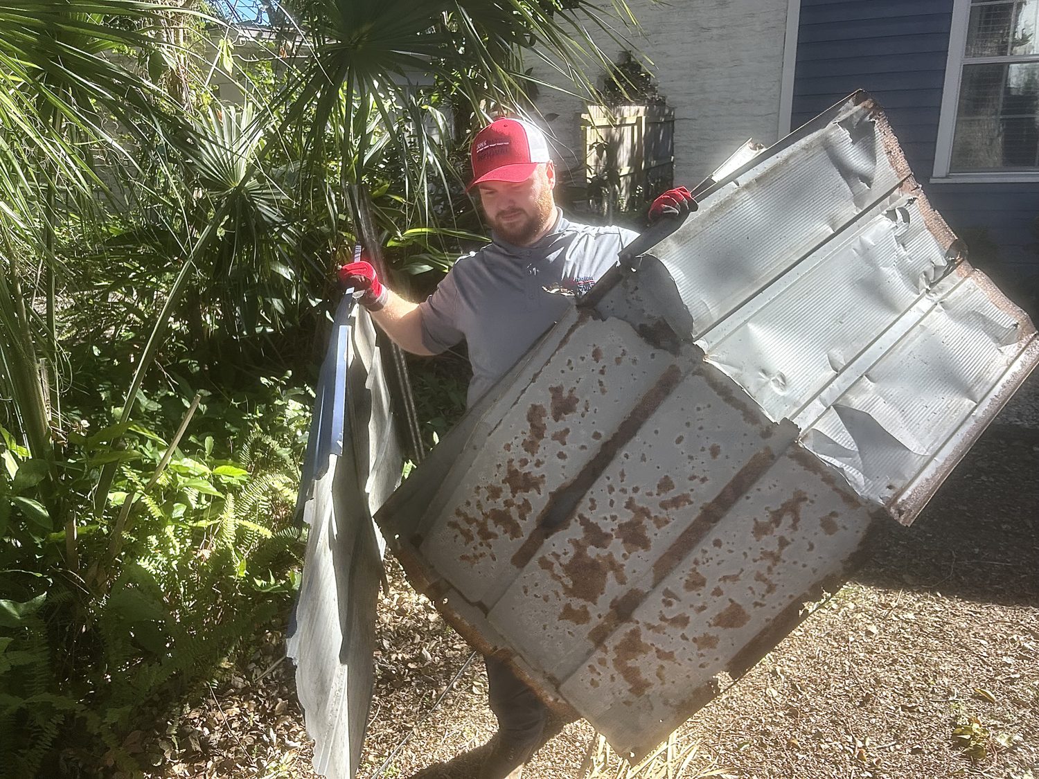Junk Nation Removal team member removing a metal shed panel from a backyard
